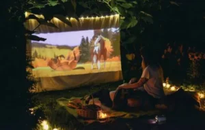 Persona viendo una película animada en un cine al aire libre con proyector, rodeada de luces cálidas, mostrando cómo la inteligencia artificial puede personalizar la experiencia de entretenimiento.
