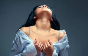 Mujer con expresión intensa y sensual, vestida con camisa blanca abierta, representando el efecto de los afrodisíacos naturales en la energía y el deseo.