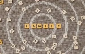 Piezas de juegos de palabras esparcidas sobre una alfombra con círculos concéntricos, destacando la palabra “FAMILY” en el centro.